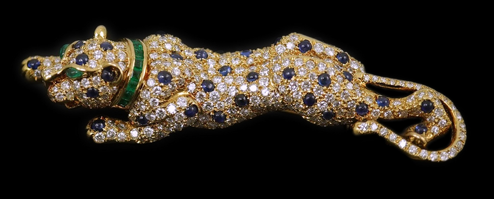 A modern Cartier style 18k gold, sapphire, emerald and diamond cluster set stalking panther brooch